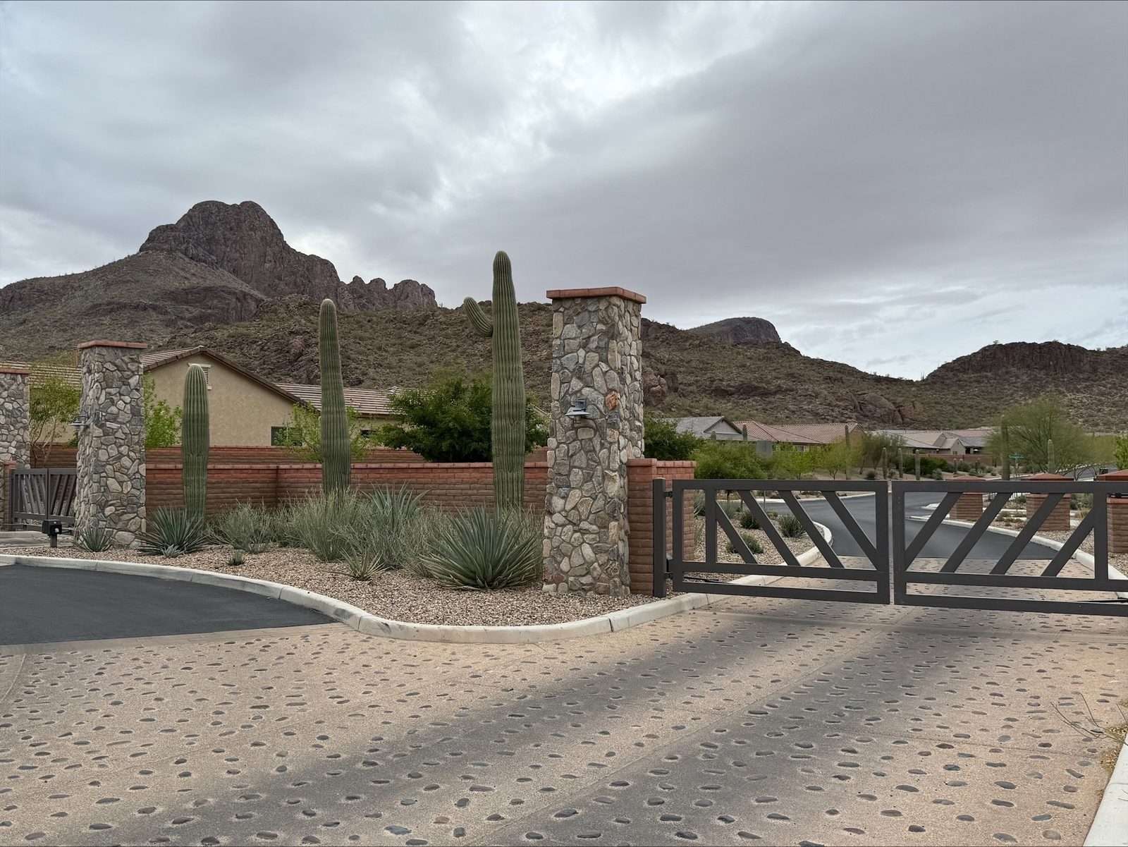 Stone-pillar community entry gate with saguaros and mountain backdrop — Signal Gates